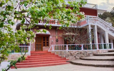 The main entrance of Leela Orchard house with blooming apple blossoms